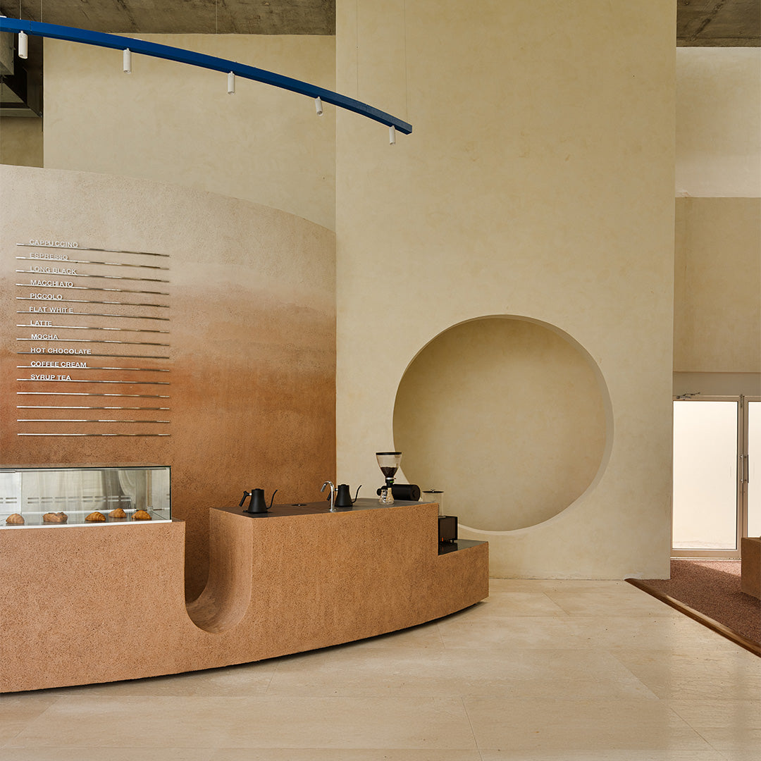 Eventide Coffee interior in Chennai with off-elliptical counter, textured earth-toned walls and circular opening, designed by Billboards
