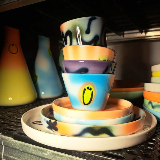 A stack of Frizbee Ceramics espresso cups, showcasing various 90s-inspired gradient glazes and a signature yellow smiley face motif